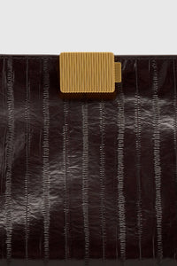 Cropped view CAMILLA AND MARC Poppy Eel Clutch in Burgundy eel‑embossed leather with ribbed gold hardware.