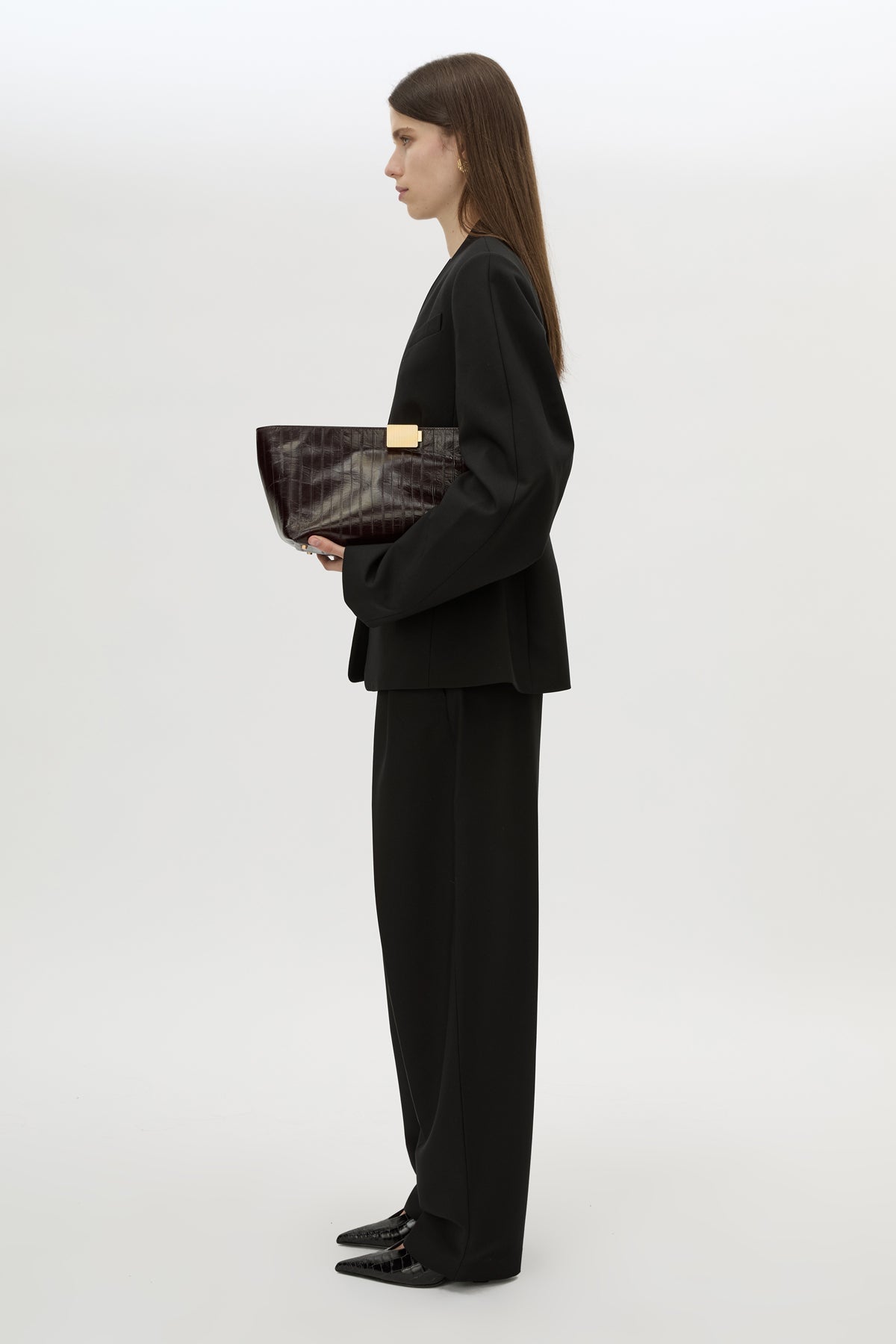 Styled view CAMILLA AND MARC Poppy Eel Clutch in Burgundy eel‑embossed leather with ribbed gold hardware.